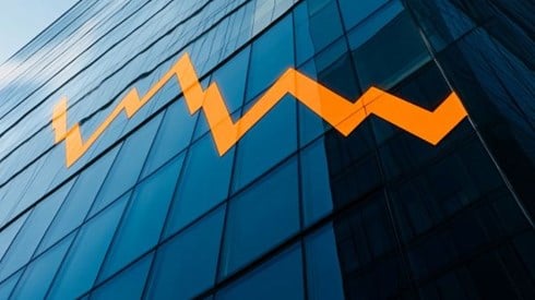 bold orange line graph declining over a blue building