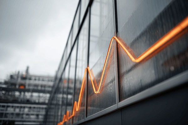 A relatively flat orange line graph on the side of a factory building