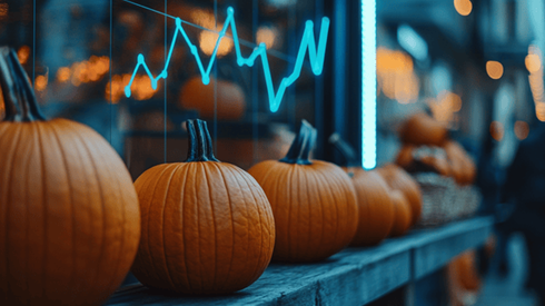 A line of pumpkins on a wooden shelf with a dipping line graph behind them