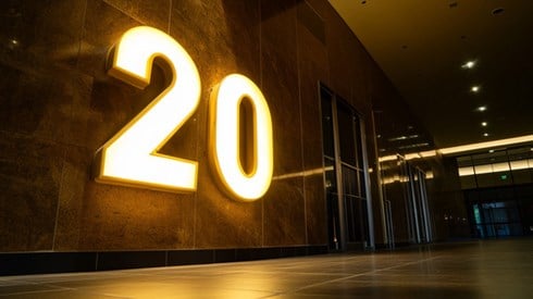 A large number "20" illuminated in golden light on the wall of an office building hallway.