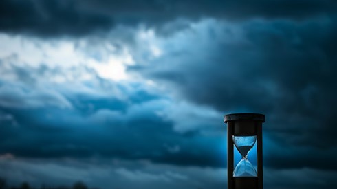 An hourglass with storm clouds in the background.