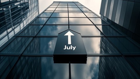 The word July with an arrow pointing up above it on the side of an office building
