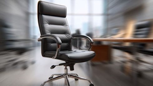 black leather executive chair in a modern office with the background motion-blurred behind it