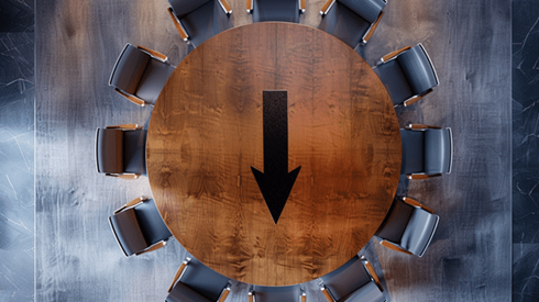 Top view of a wooden circular boardroom table surrounded by chairs with a black arrow pointing down