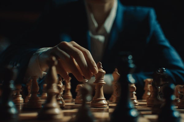 A businesswoman wearing a dark-blue suit playing chess