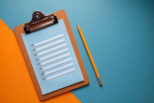 clipboard with a list of checked boxes and a pencil on an orange and blue background