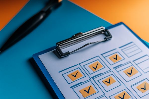 clipboard with orange boxes checked off next to a black pen