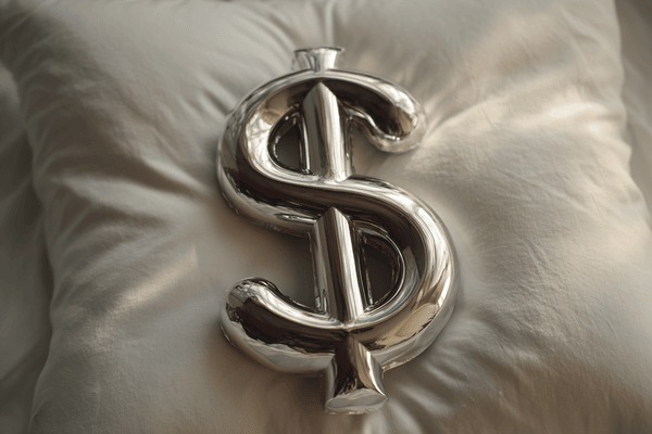 A metal dollar sign on top of a soft pillow