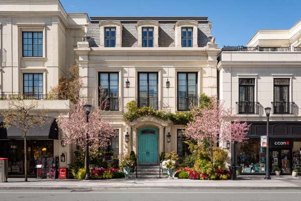 facades of a residence between retail storefronts on a sunny day