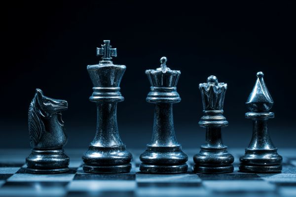 five chess pieces lined up on a chessboard under blue lights