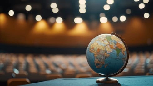 A globe sitting on a stage with empty chairs in the background