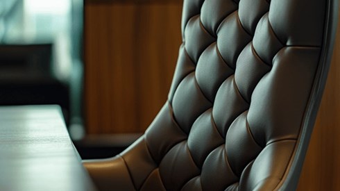 Closeup of a high-backed brown leather chair at a conference table