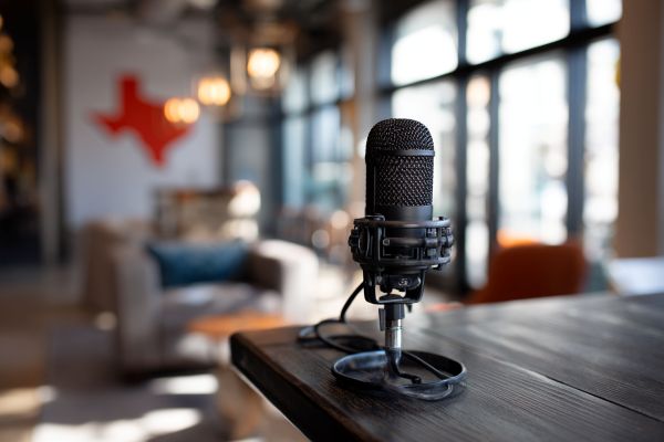 black podcast microphone on a table in a lobby with the outline of the state of Texas on the wall in the background