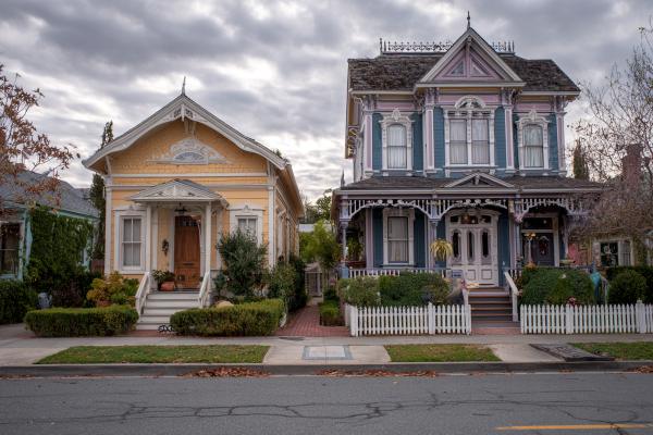 smaller yellow simpler house next to a larger more ornate Victorian house