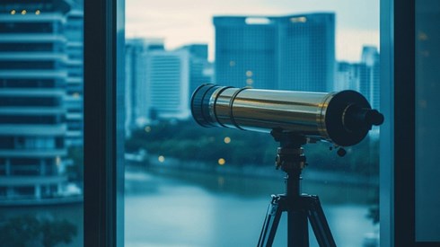 A telescope pointed to look outside of an office window