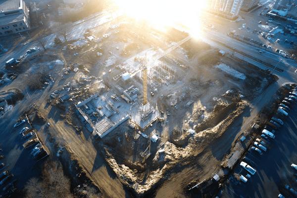 A bird's-eye view of the sun rising in the morning over a large construction worksite
