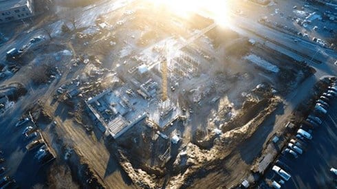 A bird's-eye view of the sun rising in the morning over a large construction worksite