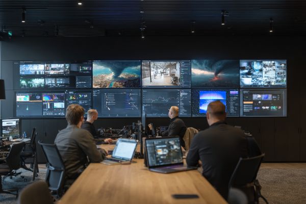 data analysts looking at multiple screens in a tech room reviewing catastrophe footage and information