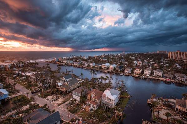 coastal neighborhood home destruction after a hurricane, clouds and storm in distance