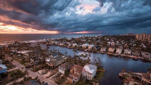 coastal neighborhood home destruction after a hurricane, clouds and storm in distance