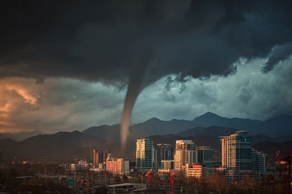 skinny tornado cloud moving over a city