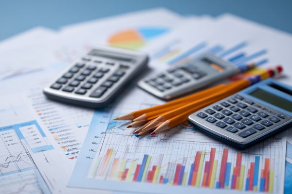calculators and pencils on top of financial papers with charts and graphs