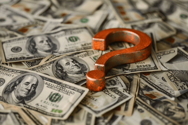 Orange metal question mark on top of a pile of money
