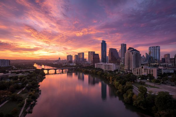 skyline of Austin Texas over the river at sunrise with pink and purple clouds in front of the rising sun