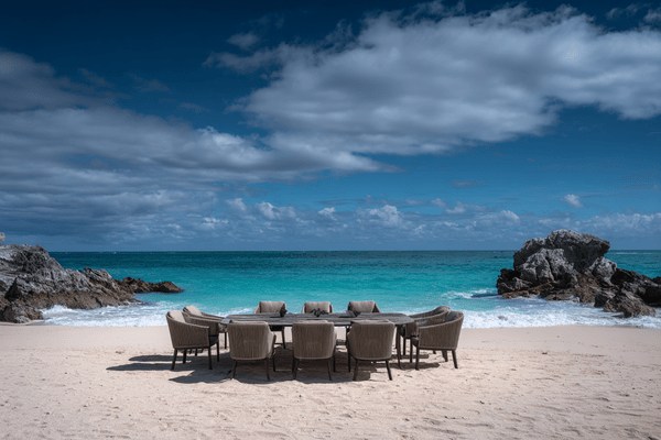 A conference table surrounded by empty chairs on a beach
