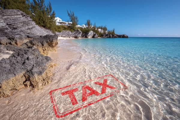 beach with sand and a house in the distance, red tax stamp superimposed under the water