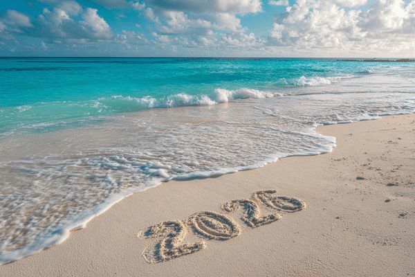 A beach in the Cayman Islands with white sand and turquoise water with the number 2026 drawn into the sand