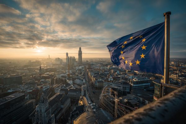 European Union flag overlooking a European city at sunrise
