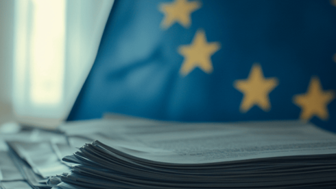 A stack of paperwork in front of the flag of the European Union