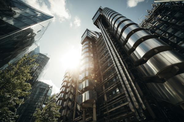exterior of Lloyd's of London building with sun shining behind it