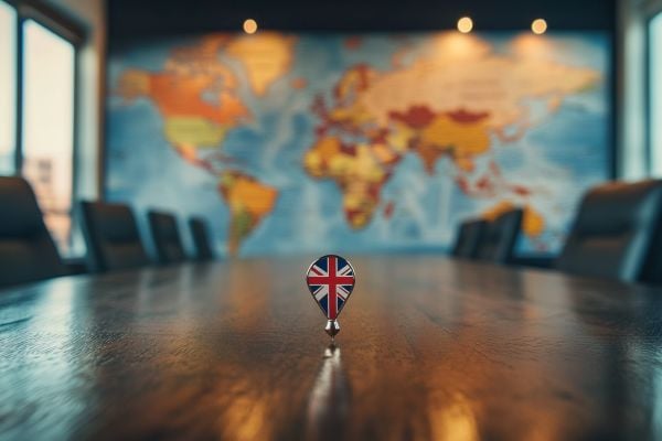 UK flag on a pin on a conference table in front of a map of the world