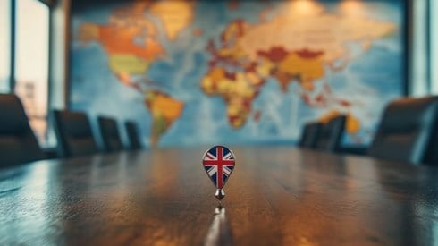 UK flag on a pin on a conference table in front of a map of the world