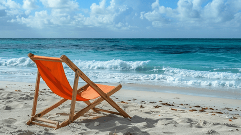 A wooden beach chair with orange canvas sitting on a beach while ocean waves roll in
