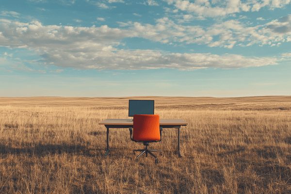 A desk with a computer monitor on it in the middle of the plains