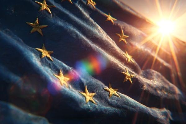 close up view of the European Union flag in front of the sun with a rainbow prism of light