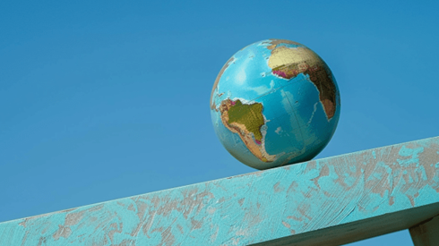 A globe rolling down a blue ramp