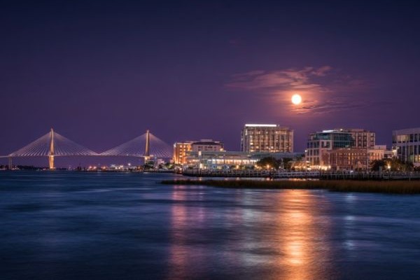 skyline of Charleston, South Carolina at night with a full moon over the river