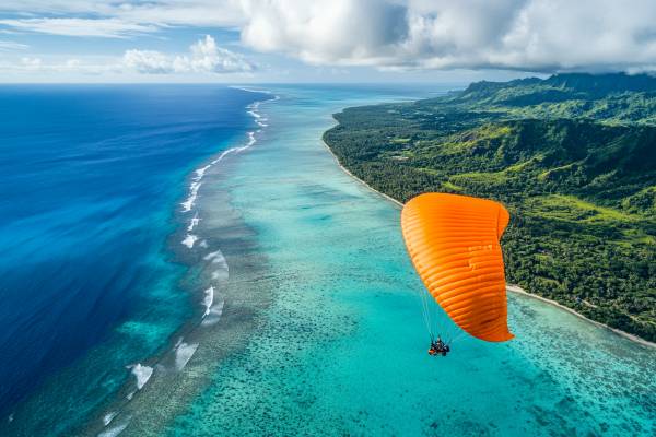 orange parasail parachute over a Cook Islands beach