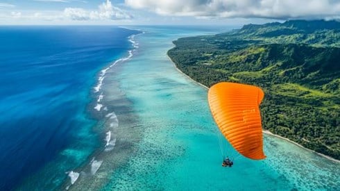 orange parasail parachute over a Cook Islands beach