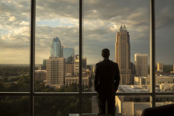 silhouette of a businessman looking through a window out to the Raleigh, North Carolina skyline