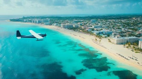 small passenger plane flying over Cayman Islands beach