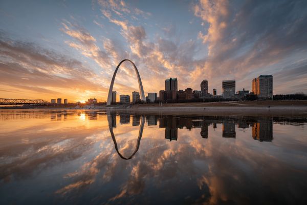 picturesque view of the St Louis Arch at sunrise with clouds and reflection in the river