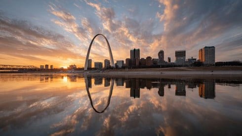 picturesque view of the St Louis Arch at sunrise with clouds and reflection in the river