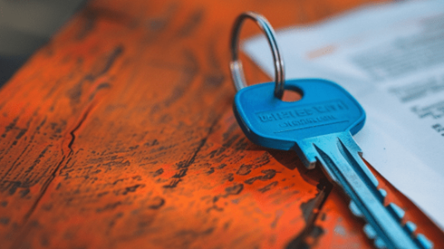 A key on top of wooden desk next to a ontract
