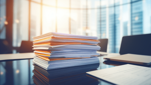 A Stack of Documents Rests Atop a Conference Room Table with Floor-to-Ceiling Windows Looking Out on Skyscrapers in Background