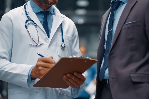 doctor holding a clipboard speaking with a businessman